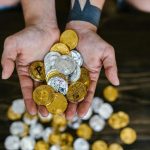 Close-up of a person holding gold and silver Bitcoin tokens, representing institutional interest in digital assets