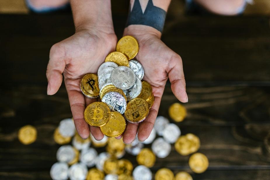 Close-up of a person holding gold and silver Bitcoin tokens, representing institutional interest in digital assets
